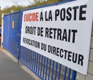 Une affiche placardées sur des grilles indique : « Suicides à La Poste. Droit de retrait. Révocation du directeur.