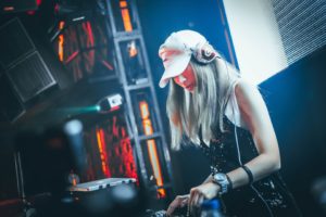 Jeune femme DJ mixe de la musique dans une ambiance électronique.