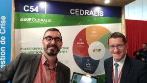 deux hommes devant le poster de la société Cedralis durant APS 2019