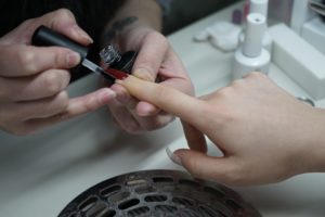 Pose de faux ongles au dessus d’une table respirante.