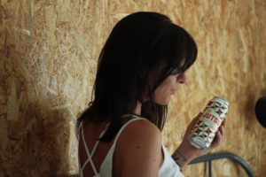 Une jeune femme tient une canette de bière.